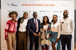Sechs Teilnehmende des „African Students Day 2026“ stehen vor einer Fotowand mit Veranstaltungslogo und Partnern und lächeln in die Kamera.